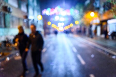 Urban night scene with people walking out of focus with colored background.の写真素材