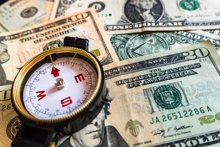 Close-up of a compass on dollar bills, guide for making smart investment decisions.の写真素材