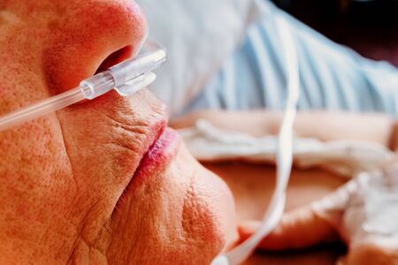 Detail of a patient breathing oxygen through a plastic nasal cannula, elderly woman with breathing...