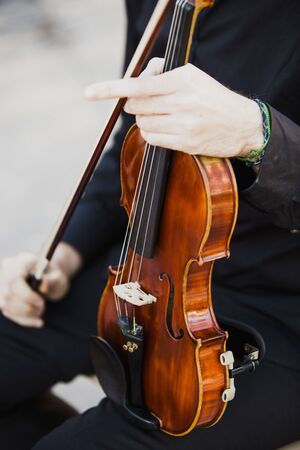 Classical musicians hold their musical instrument, a violin, while reading their score.の写真素材