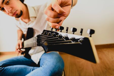 Guitarist posing with his electric guitar, white background.