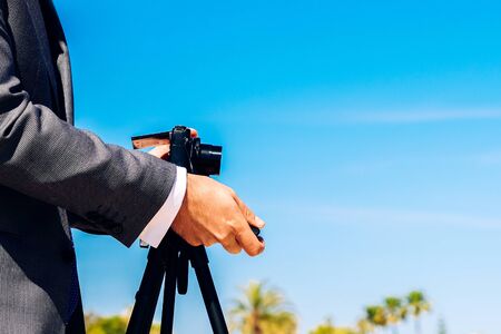 Man in a suit using a compact photo camera on a tripod to take a self-portrait to use as a profile in his business and social networks.の写真素材