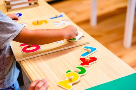 Hand of 2 year old boy in elementary class using a toy to develop motor skills.