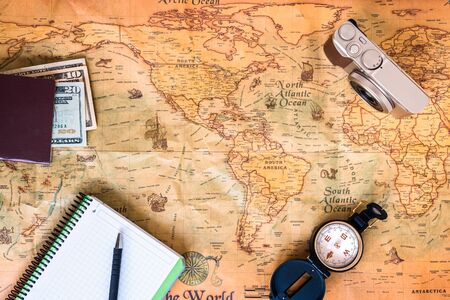 A traveler plans his trip around the world on an old map, while taking notes to get inspired.