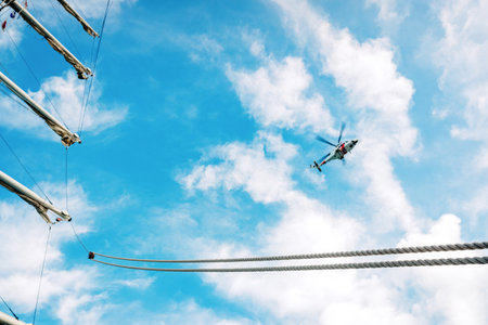 Valencia, Spain - November 2, 2019: Rescue helicopter flying over a sailboat, seen from the sea.のeditorial素材