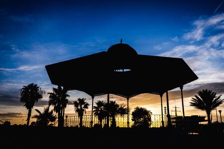 Silhouette of a pergola at sunset on a cloudy afternoon in the port of the Marina Real of Valencia, Spain.の写真素材
