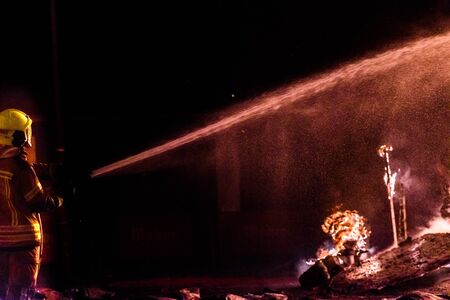 Firefighter with his protective suit working controlling the burning of a Falla during the Valencian fiestas.の写真素材