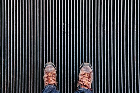 A man stops on a vent plate in dark lines and looks down.