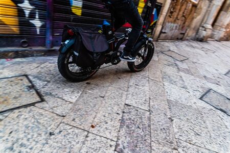 Bari, Italy - March 12, 2019: young man driving an electric motorcycle through the streets of a...