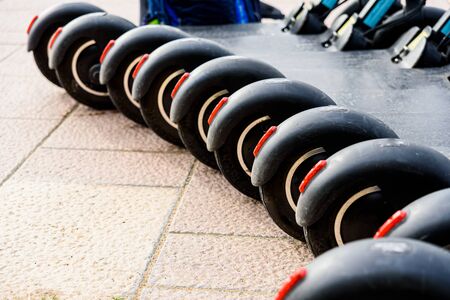 Several black electric scooters parked in a row, for rent.