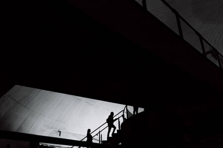 Silhouettes of people inside a building crossing stairs and walkways.の写真素材