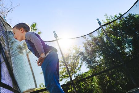 Child having fun in summer on a trampoline at sunset.の写真素材