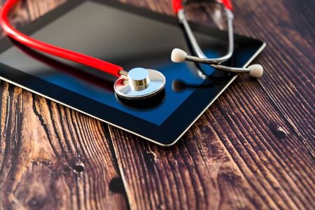 Red stethoscope on a table isolated on wooden background.の写真素材