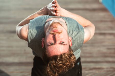 Portrait of a young man practicing yoga doing a concentrated Ustrasana, Camel Pose or back bending...