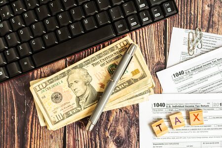 Dollar bills on a table in which the 1040 American tax payment form is filled out.の写真素材
