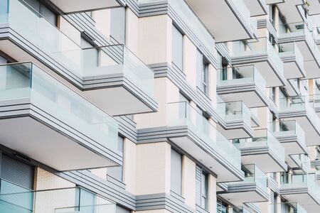 Detail of the design of the facade of a building with glass balconies arranged in a symmetrical pattern of white colorの写真素材