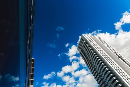 A deep blue sky is reflected in the clean glass walls of a building in a big city.