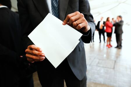 Businessman hand draws an invitation from a white envelope. Blank template to fill with text, people...