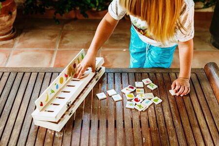 Hands of a child using a wooden toy to match images, used in educational alternative pedagogies, in...