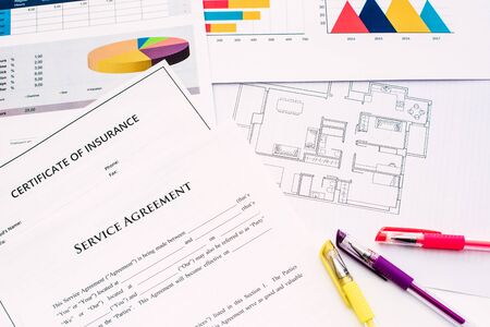 Architects work at a desk on plans and financial documents of their buildings.