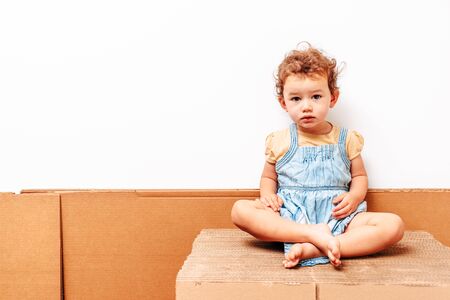 Portrait of 1 year old girl with white background, playing on some cardboard, copy space.の写真素材