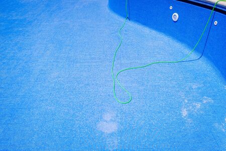 A hose to clean an empty swimming pool in summer.の写真素材