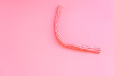 Elongated pink candy isolated on a flat colored background.の写真素材