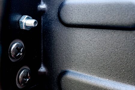 Detail of some tight screws in a black metal structure.