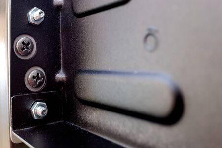 Screws and nuts screwed to a black metal plate.