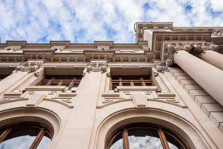Facade of large institutional building with large columns and windows, background sky, low angle...
