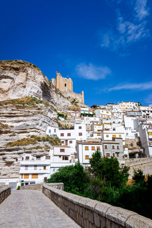 View of the tourist Spanish city of Alcala del Jucar, with its castle and white houses from the medieval bridge.のeditorial素材