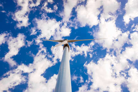 High modern windmills spinning to generate electricity viewed from below.の写真素材