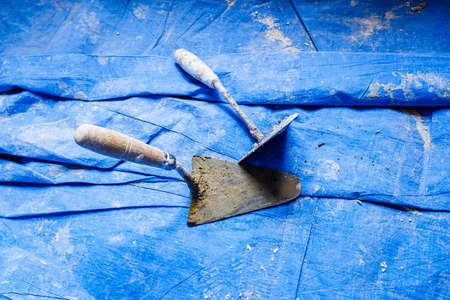 Dirty tools of bricklayers on blue blanket during a cement work.の写真素材