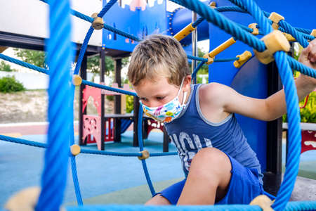 Boy with protective mask plays carefree in a playground.の写真素材