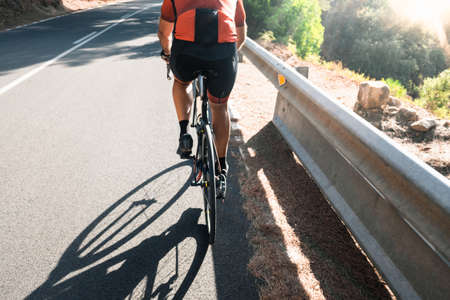Shadow of a cyclist pedaling on the asphalt of a mountain road.の写真素材
