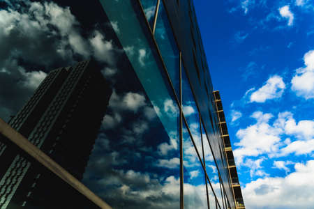 A deep blue sky is reflected in the clean glass walls of a building in a big city.の写真素材