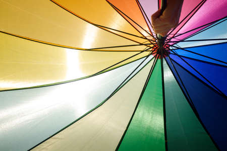 Colorful umbrella protects from the sun a summer day, blue sky background.の写真素材