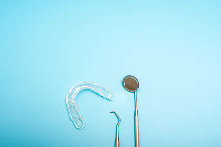 Transparent dental aligner next to dentist mirror, copy space.