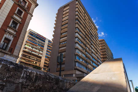 Wide old residential buildings viewed from below with the sky and sun in the background.