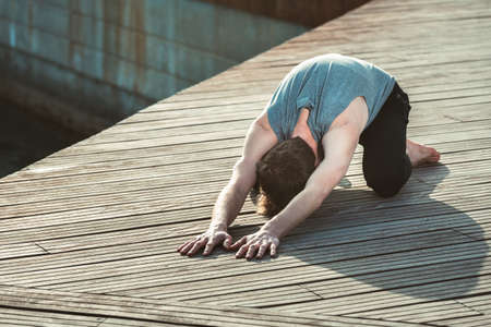 Balasana is a yoga posture to avoid back pain, a young man practices it.の写真素材