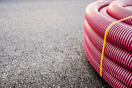 New road with roll of electrical pipes on black asphalt, copy space.の写真素材