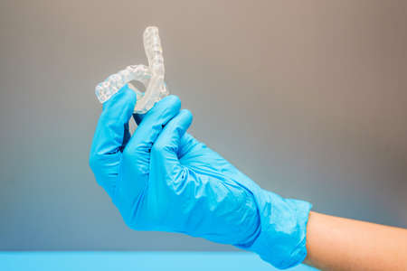 Dentist doctor hand holding a dental aligner, isolating on background.