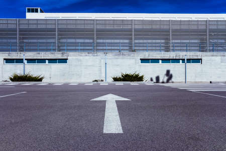A large arrow on the asphalt indicates the direction of a building.