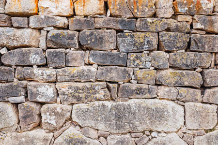 Wall of thick ancient rocks, rustic background of medieval construction.の写真素材
