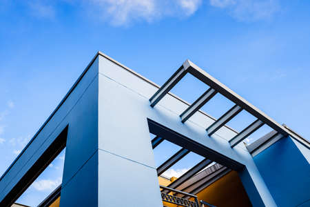 Roof of a blue painted straight design building behind a clear and clear sky at sunset.