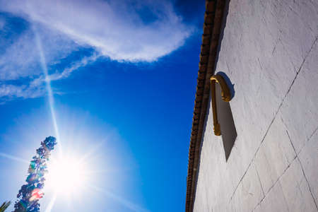 A white wall of a church illuminated by the intense sun, background of a blue sky.の写真素材