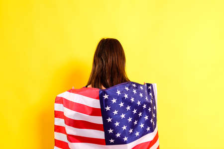 Young embarrassed woman covers herself with an American flag to maintain privacy and protect herself...