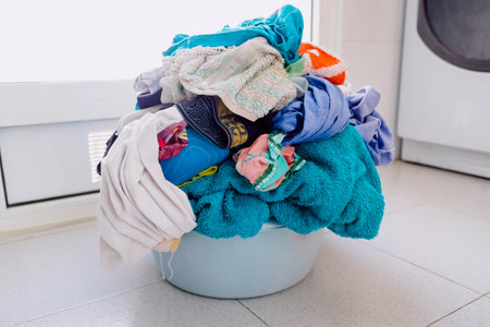 Basket with dirty clothes to put in a washing machine, resting on the floor.の写真素材