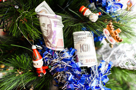 Dollar bills hanging on a Christmas tree alongside traditional Christmas decorations.の写真素材