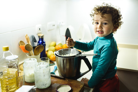 Adorable 2 year old girl cooking a cake at home overnight.の写真素材